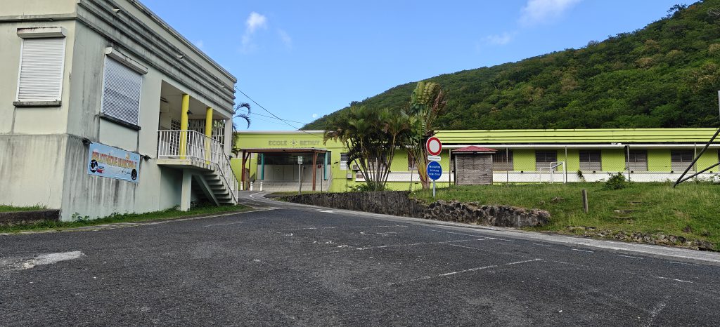 School building painted green and a car park in the foreground